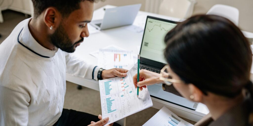 Two professionals reviewing data and graphs in a modern office setting for analysis.